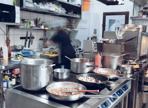 Behind the scenes of brands. The chef cooking in a professional kitchen of a restaurant meal for client or delivery. Open business from the inside. Meals during the quarantine. Hurrying up, motion.